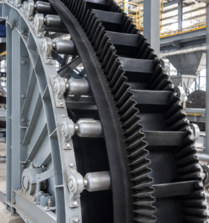 Sidewall conveyor belt with corrugated sidewalls and cleats for steep-angle material conveying